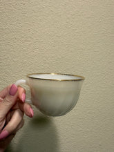 Load image into Gallery viewer, vintage 1940-1970s Fire-King white milk glass teacup, featuring the "Swirl" or "Golden Anniversary" pattern with 22k gold rim trim produced by Anchor Hocking coffee scented candle
