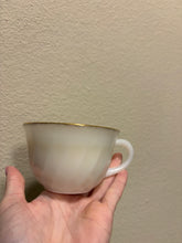 Load image into Gallery viewer, vintage 1940-1970s Fire-King white milk glass teacup, featuring the "Swirl" or "Golden Anniversary" pattern with 22k gold rim trim produced by Anchor Hocking coffee scented candle
